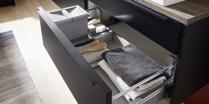 Zwarte badkamermeubels zijn echt trendy. De matte oppervlakken zien er heel cool uit in contrast met de vitrinekast Flat met zijn uiterst slanke aluminium frame. Ronde afsluitwangen zorgen voor een huiselijk karakter.